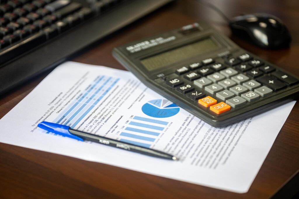 A calculator, pen, and financial data charts on a desk used to calculate lost earning capacity beyond no-fault limits after a Long Island car accident.