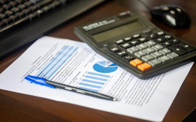 A calculator, pen, and financial data charts on a desk used to calculate lost earning capacity beyond no-fault limits after a Long Island car accident.